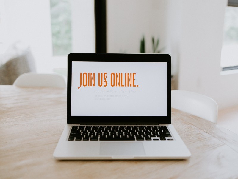 Laptop computer with 'Join us online' written in orange font on the screen