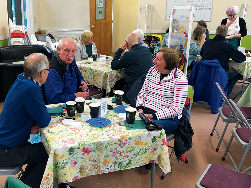 People sat around tables enjoying a hot drink and a chat